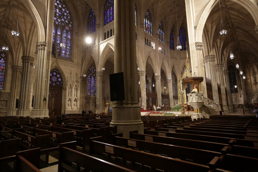 Archbishop Timothy Dolan, right, delivers his homily over mostly empty pews as he leads an Easter Mass at St. Patrick's Cathedral in New York on April 12, 2020. (AP Photo/Seth Wenig)