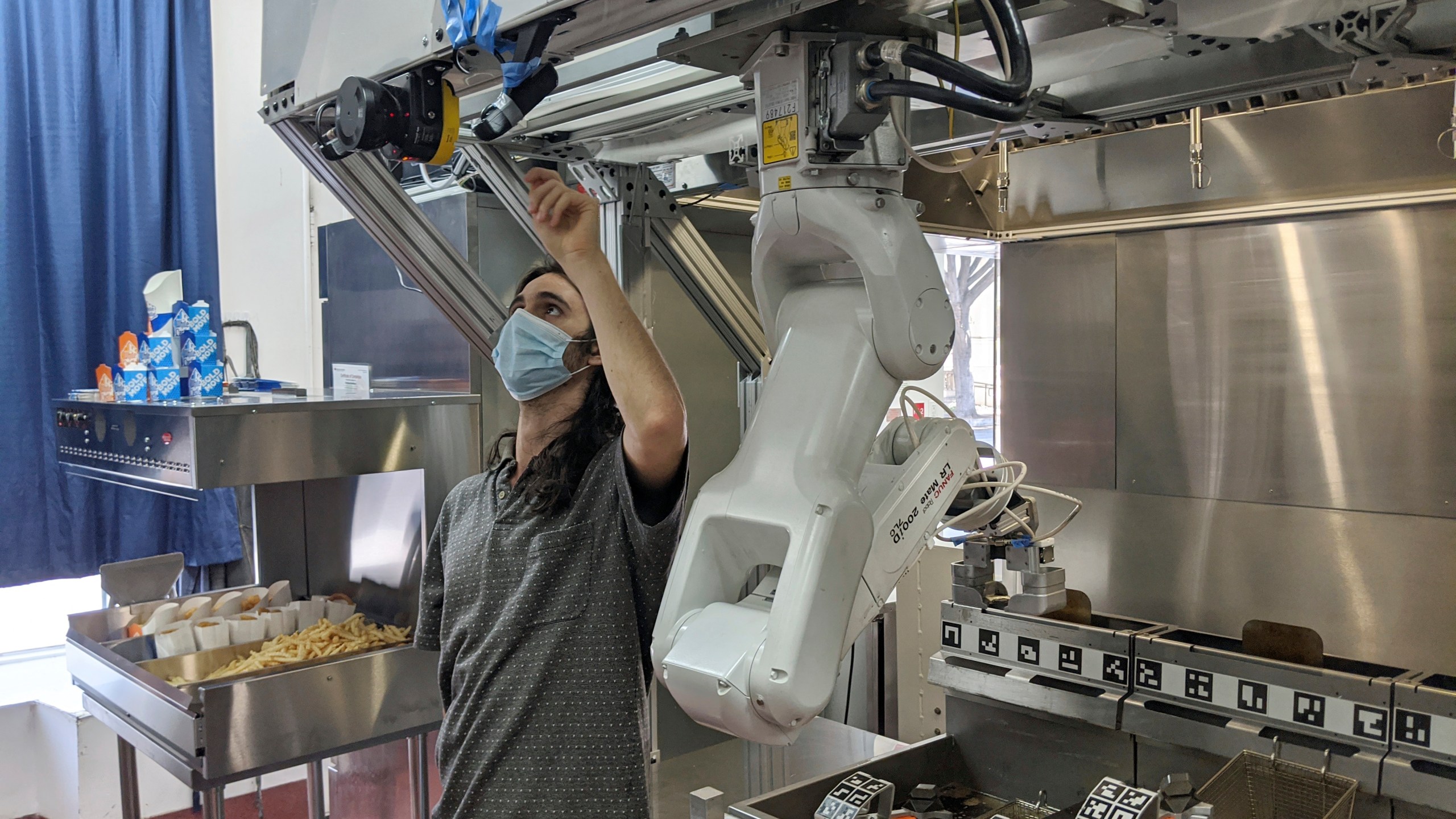 A technician makes an adjustment to a robot at Miso Robotics' White Castle test kitchen in Pasadena on July 9, 2020. (Miso Robotics via AP)