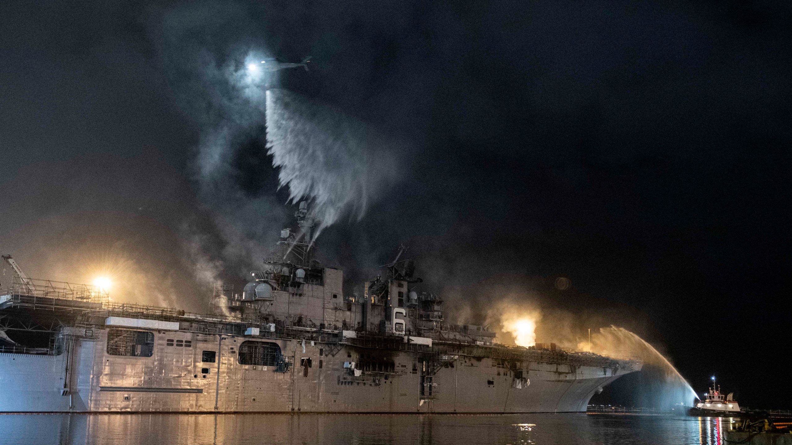 A helicopter from Helicopter Sea Combat Squadron 3 combats a fire aboard the amphibious assault ship USS Bonhomme Richard at Naval Base San Diego on July 14, 2020. (Mass Communications Specialist 3rd Class Garrett LaBarge/U.S. Navy via AP)