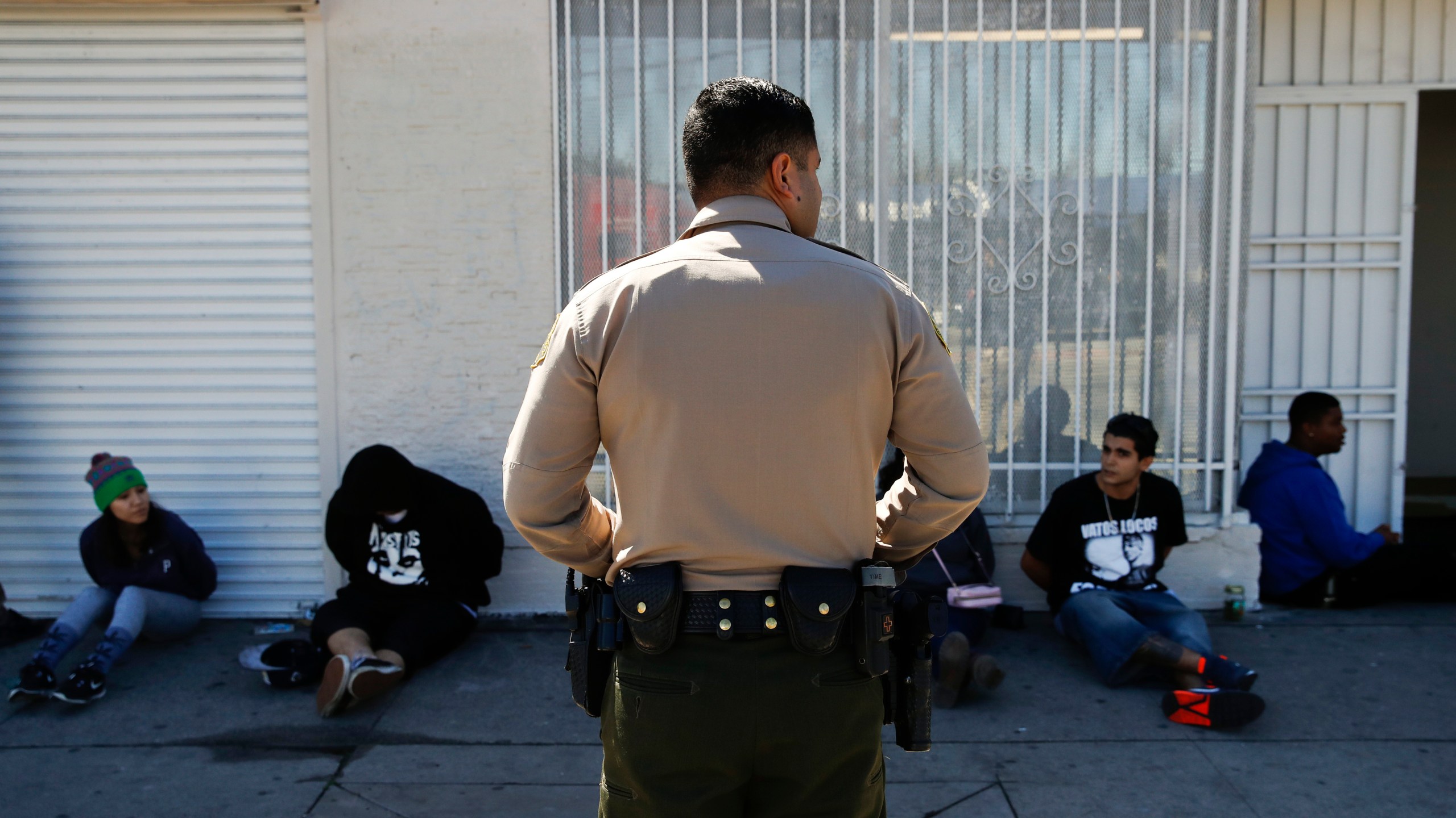 A Los Angeles County Sheriff's deputy keeps watch on a group of people apprehended at an illegal marijuana dispensary in Compton in this March 15, 2018, file photo. (Jae C. Hong / Associated Press)