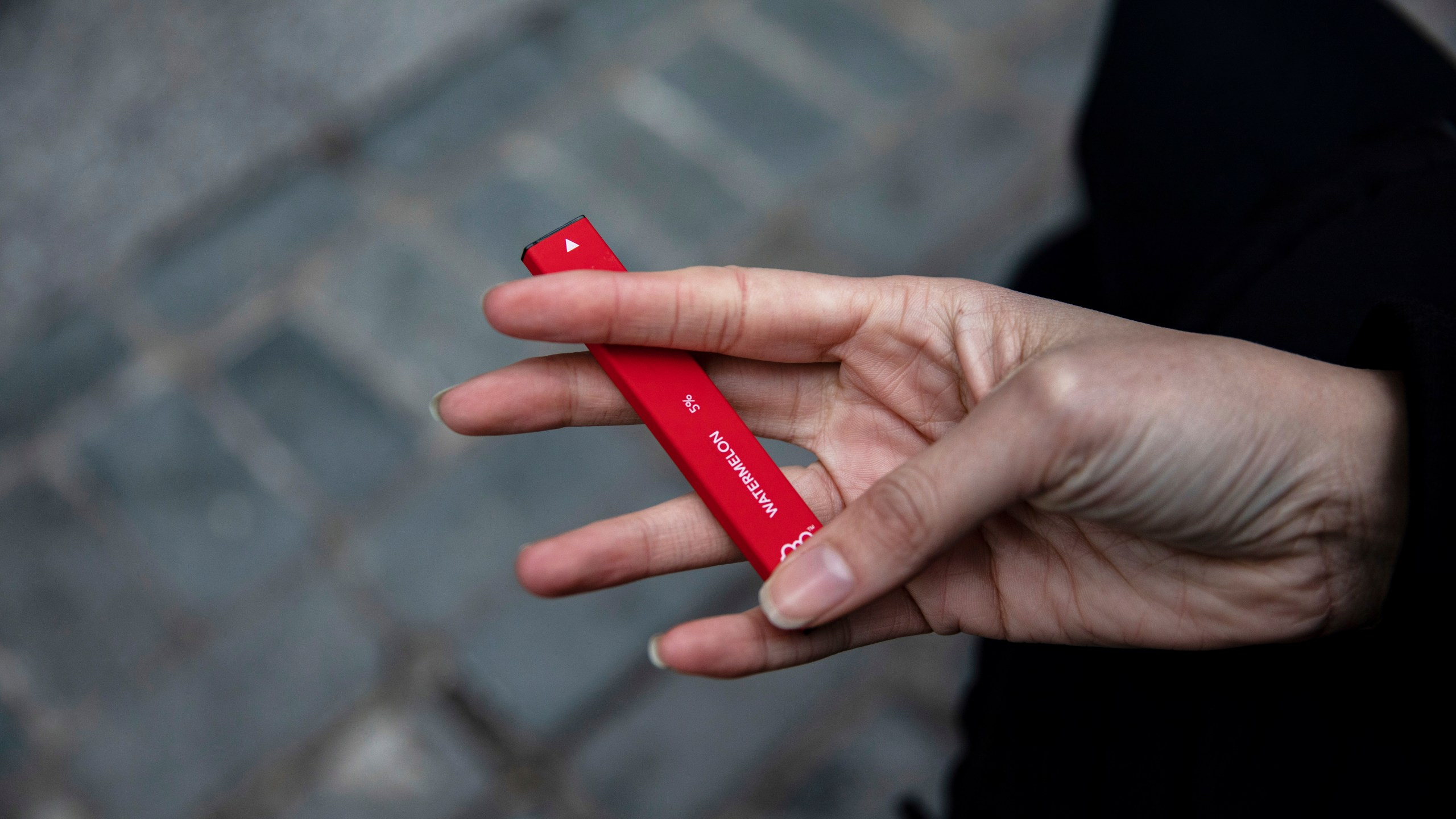 A woman holds a Puff Bar flavored disposable vape device in New York on Jan. 31, 2020. (AP Photo/Marshall Ritzel, File)