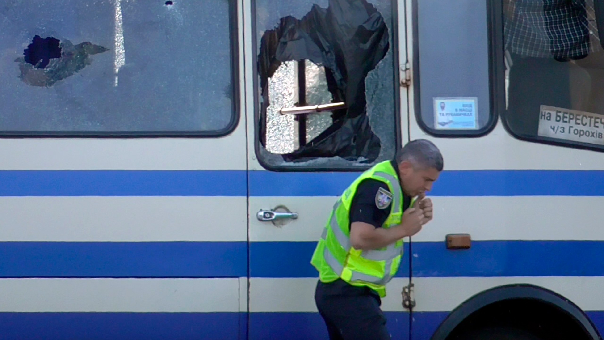 A policeman, who has brought water for hostages contained after an armed man seized a long-distance bus, reacts after a gun shot that the assailant sent to keep him away in the city centre of Lutsk, Ukraine, on July 21, 2020. (Ukrainian Police Press Office via Associated Press)