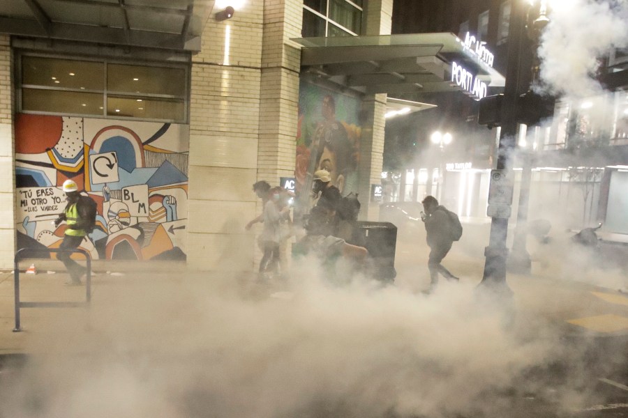 Demonstrators walk away from tear gas deployed by federal officers during a Black Lives Matter protest Sunday, July 26, 2020, in Portland, Ore. (AP Photo/Marcio Jose Sanchez)