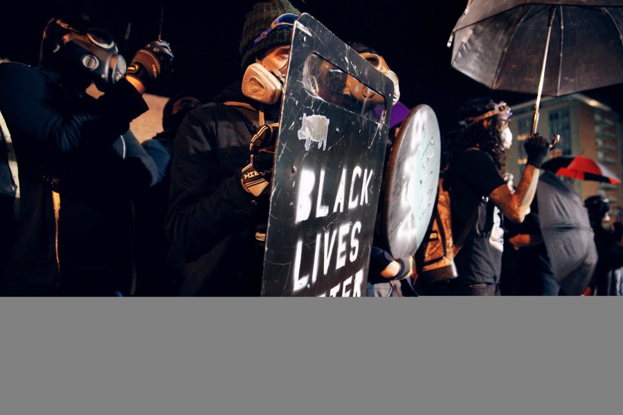 Protesters march outside the Richmond Police Department headquarters on Grace Street in Richmond, Va., Saturday, July 25, 2020.  Police deployed flash-bangs and pepper spray to disperse the crowd after a city utility vehicle was set on fire. (James H Wallace/Richmond Times-Dispatch via AP)