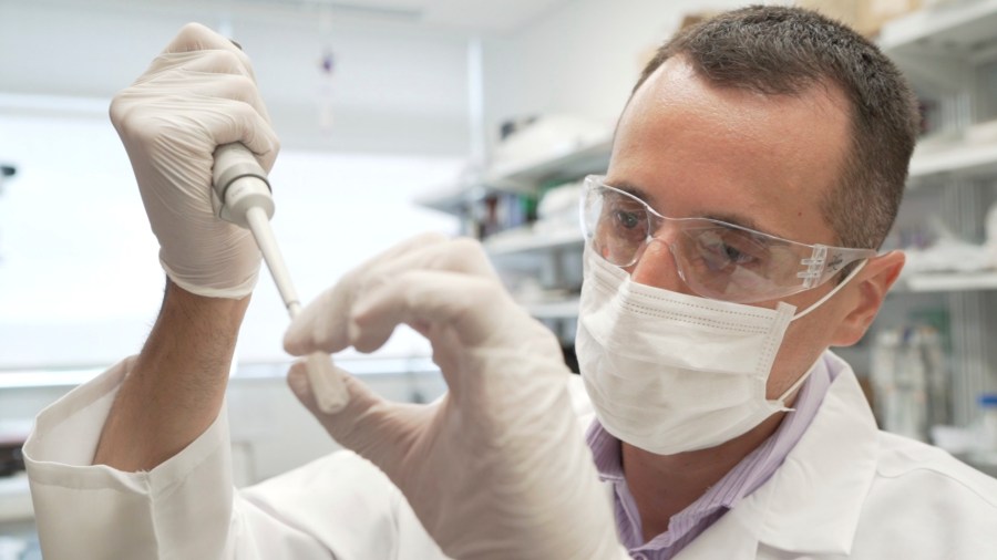 In this image from video provided by Washington University, researcher Nicolas Barthelemy works on a p-tau217 test for Alzheimer's disease at a laboratory in St. Louis, Mo., on Monday, July 27, 2020. (Huy Mach/University of Washington via AP)