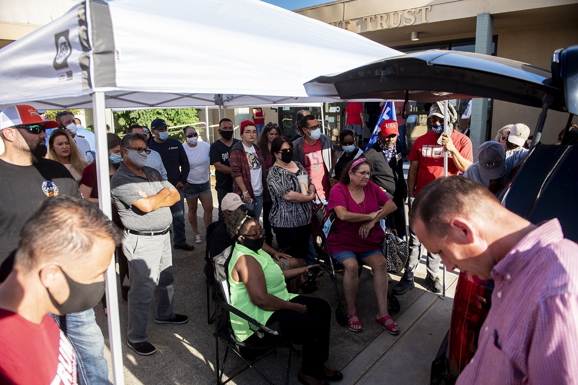 People gather around a police car to watch the Atwater City Council meeting on television outside City Hall in Atwater on July 27, 2020. (Andrew Kuhn/The Merced Sun-Star via AP)