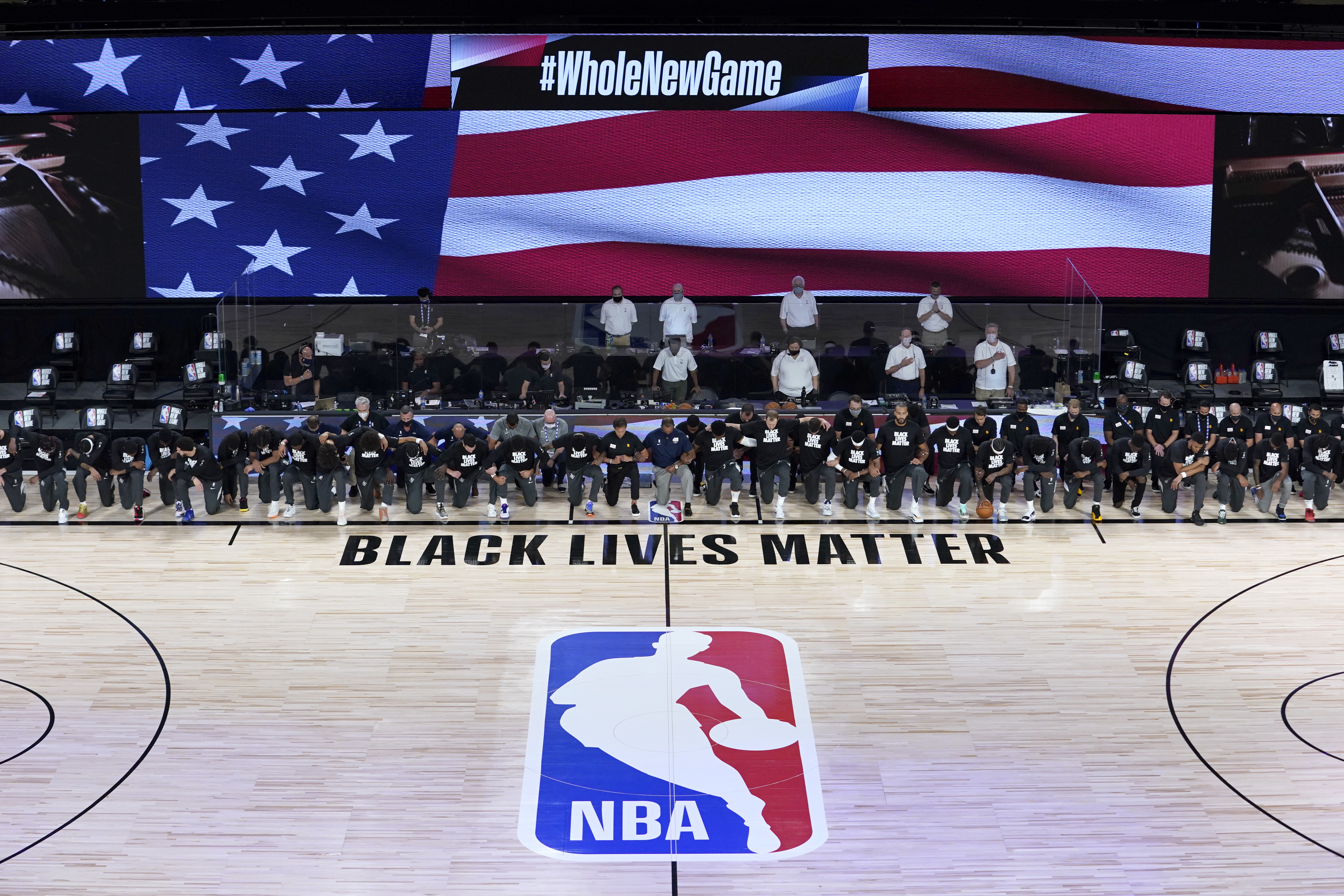 Members of the New Orleans Pelicans and Utah Jazz kneel together around the Black Lives Matter logo on the court during the national anthem before the start of an NBA basketball game on July 30, 2020, in Lake Buena Vista, Fla. (AP Photo/Ashley Landis, Pool)