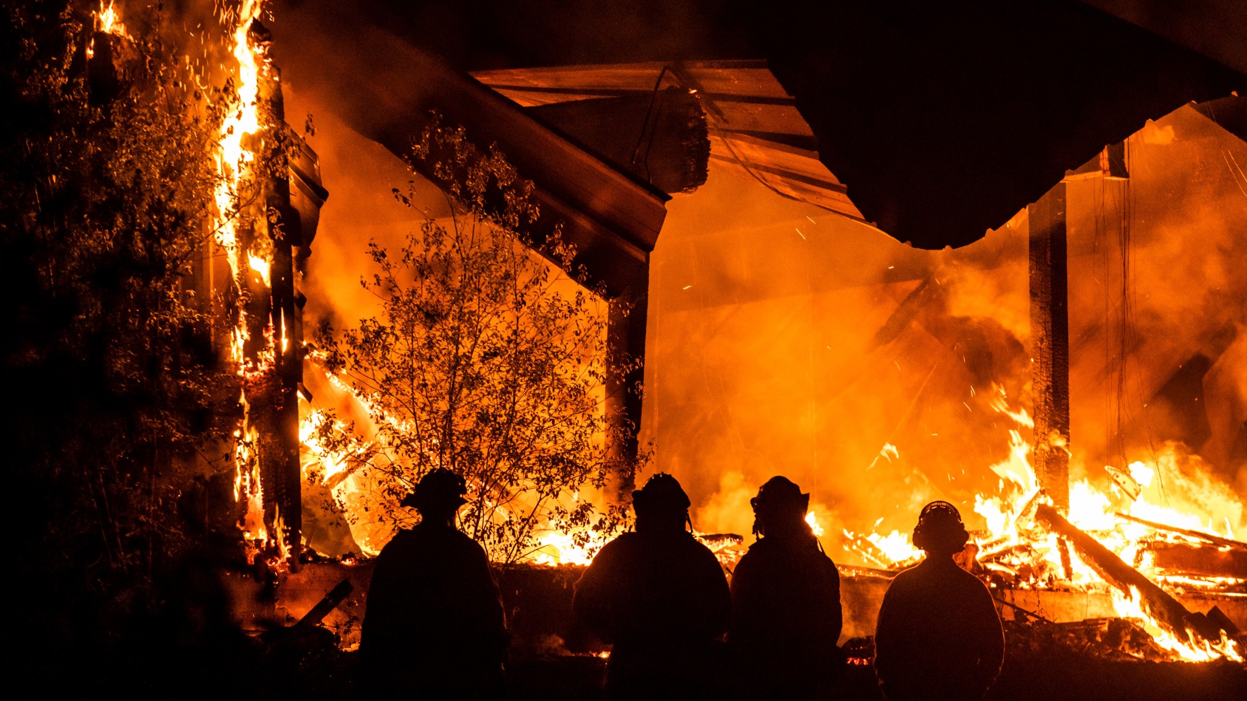 Firefighters look on as a structure burns during the Kincade Fire off Highway 128, east of Healdsburg, California on Oct. 29, 2019. Philip Pacheco/AFP via Getty Images)