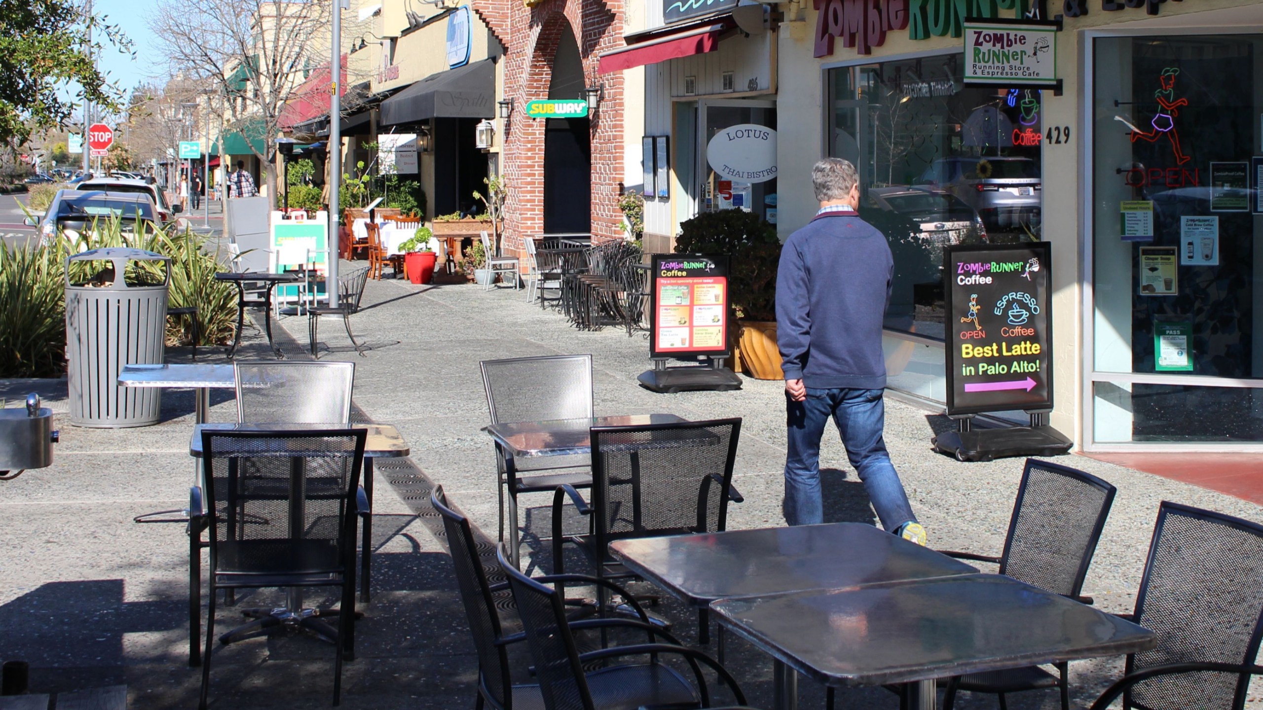 A man glances strides along a quiet sidewalk in downtown Palo Alto in Santa Clara County on March 12, 2020. (GLENN CHAPMAN/AFP via Getty Images)