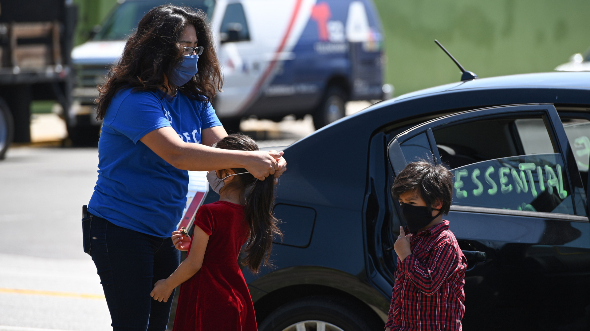 Activist Michelle Lozano puts a mask on her children Maya, center, and Iker as day laborers and their supporters participate in a "Caravan for Essential and Excluded Workers'' in Los Angeles on April 14, 2020. (Robyn Beck / AFP / Getty Images)