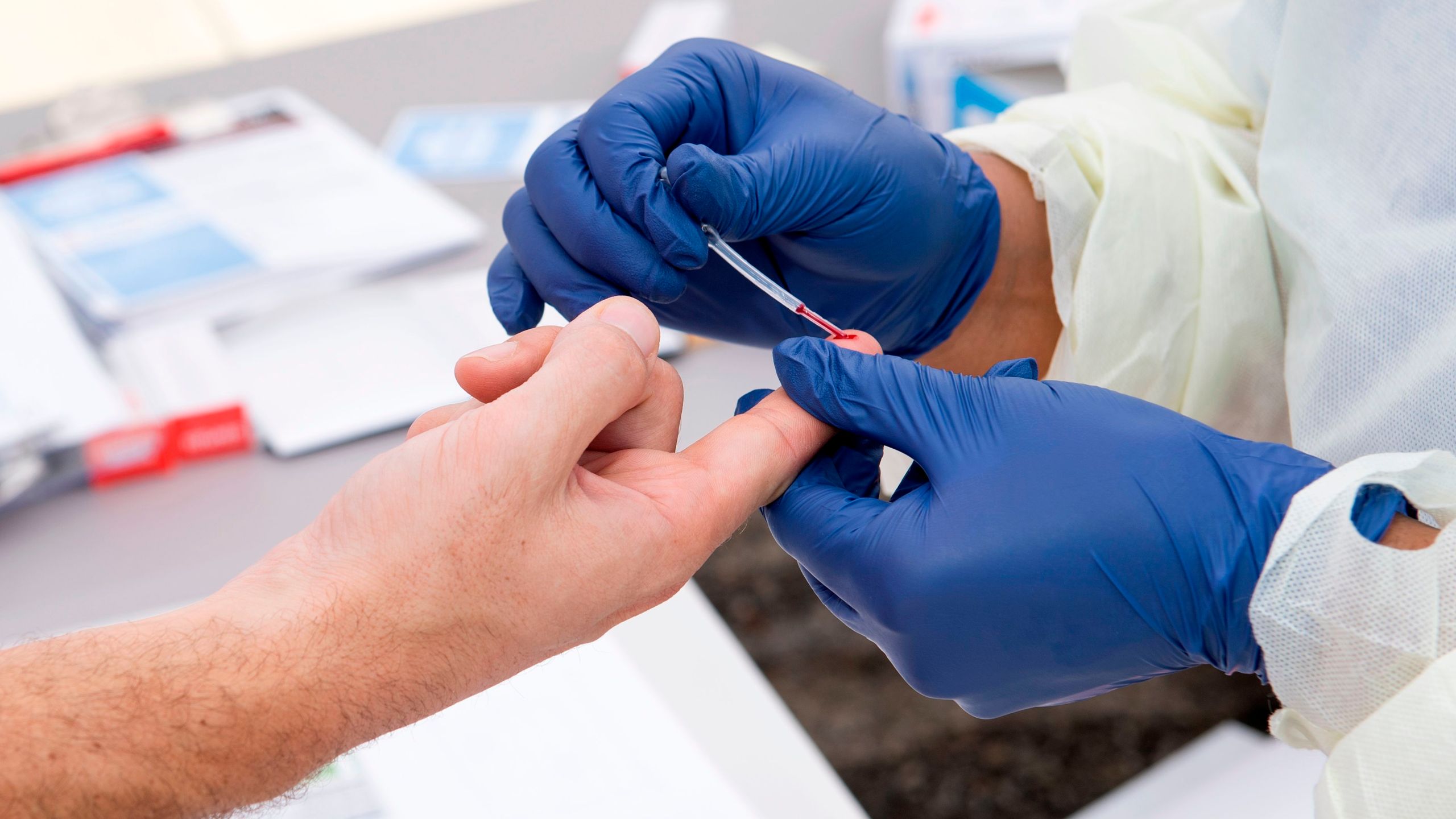 A health worker takes a drop of blood for a COVID-19 antibody test in Torrance on May 5, 2020. (Valerie Macon / AFP / Getty Images)