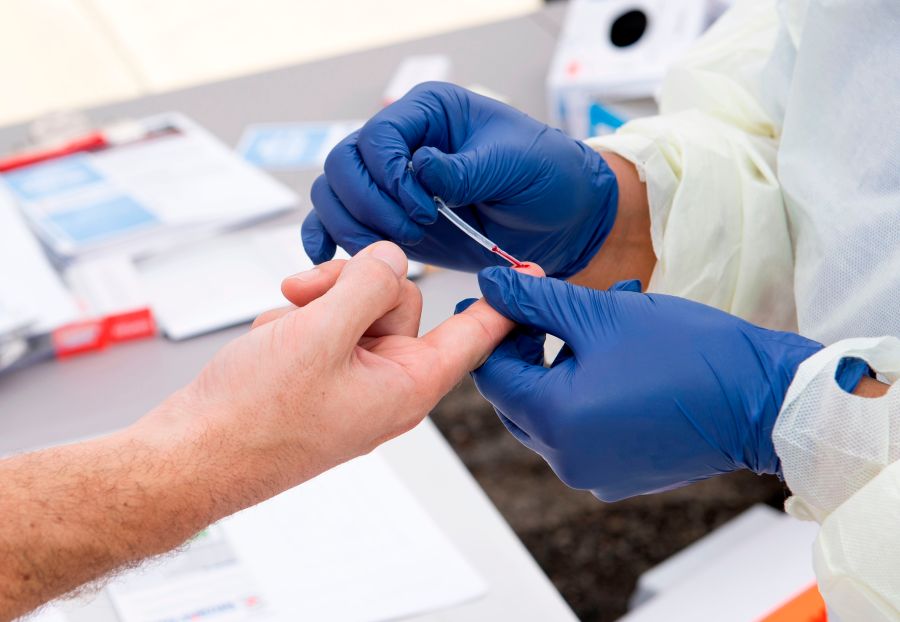 A health worker takes a drop of blood for a COVID-19 antibody test in Torrance on May 5, 2020. (Valerie Macon / AFP / Getty Images)