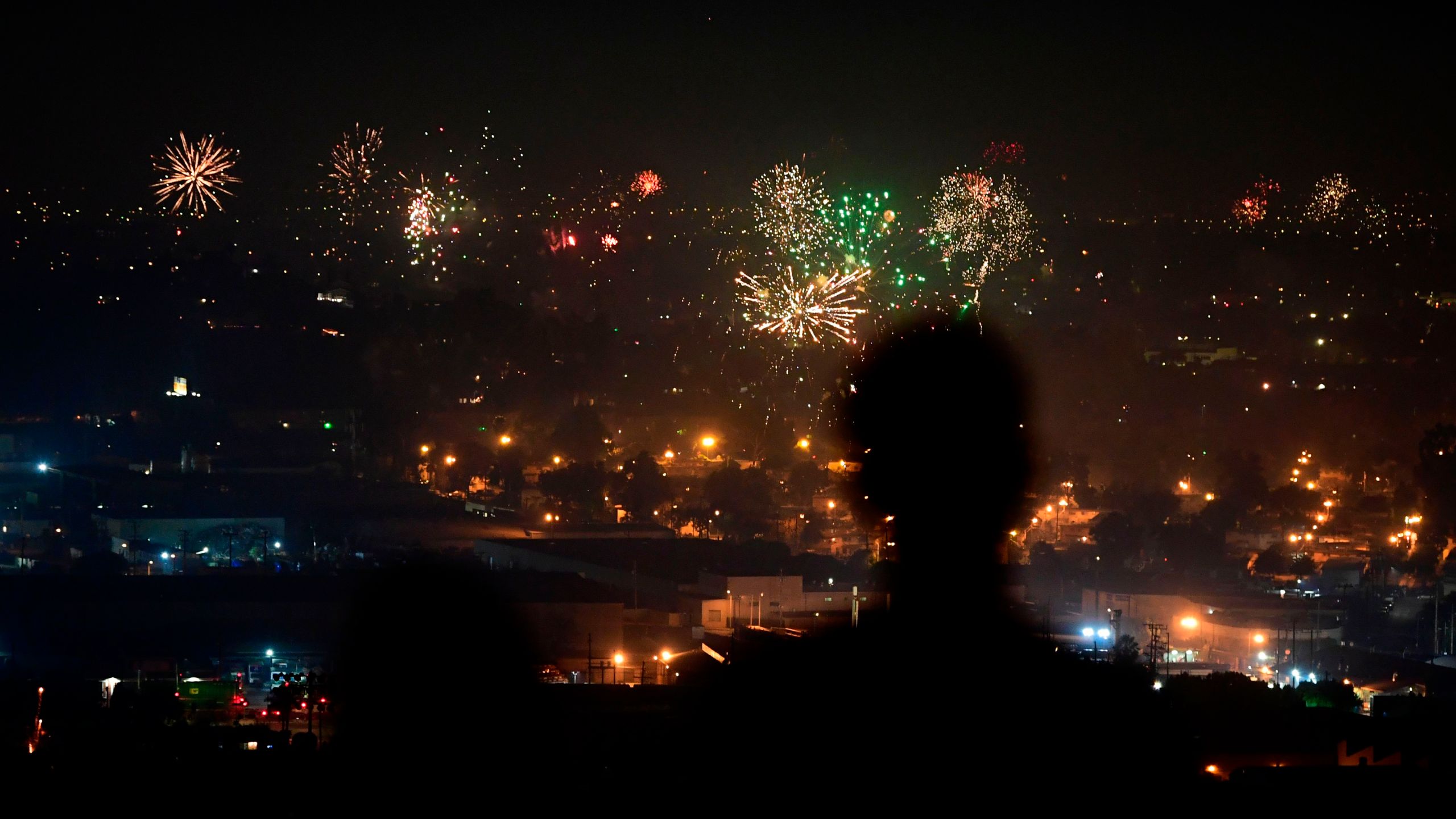 People watch fireworks burst over Los Angeles on July 4, 2020. (Frederic J. Brown / AFP / Getty Images)