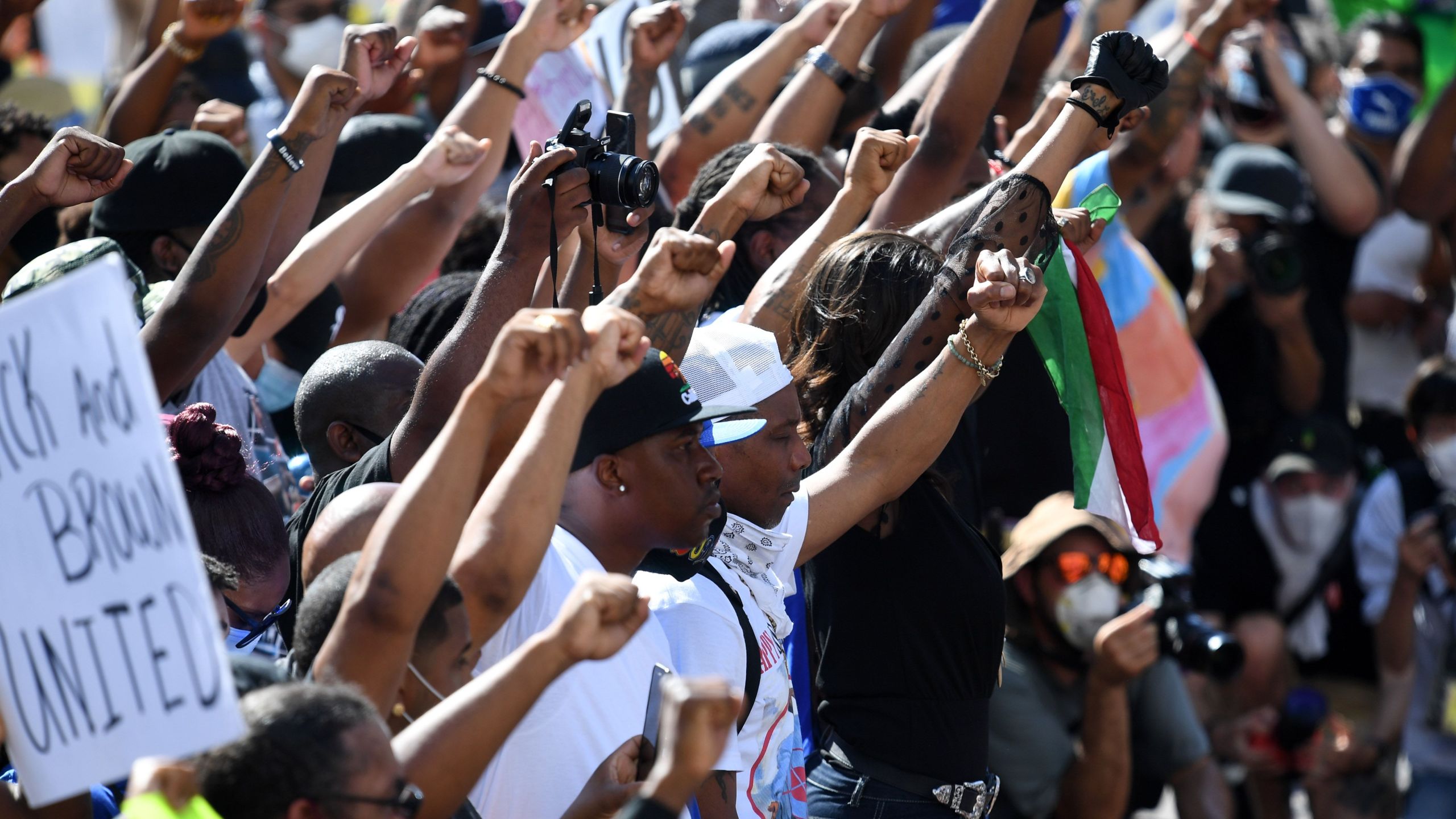 Activists and supporters of the Black and Brown Unity March raise their fists as the two groups march from different directions to meet in front of Los Angeles City Hall on July 12, 2020. (Robyn Beck / AFP / Getty Images)