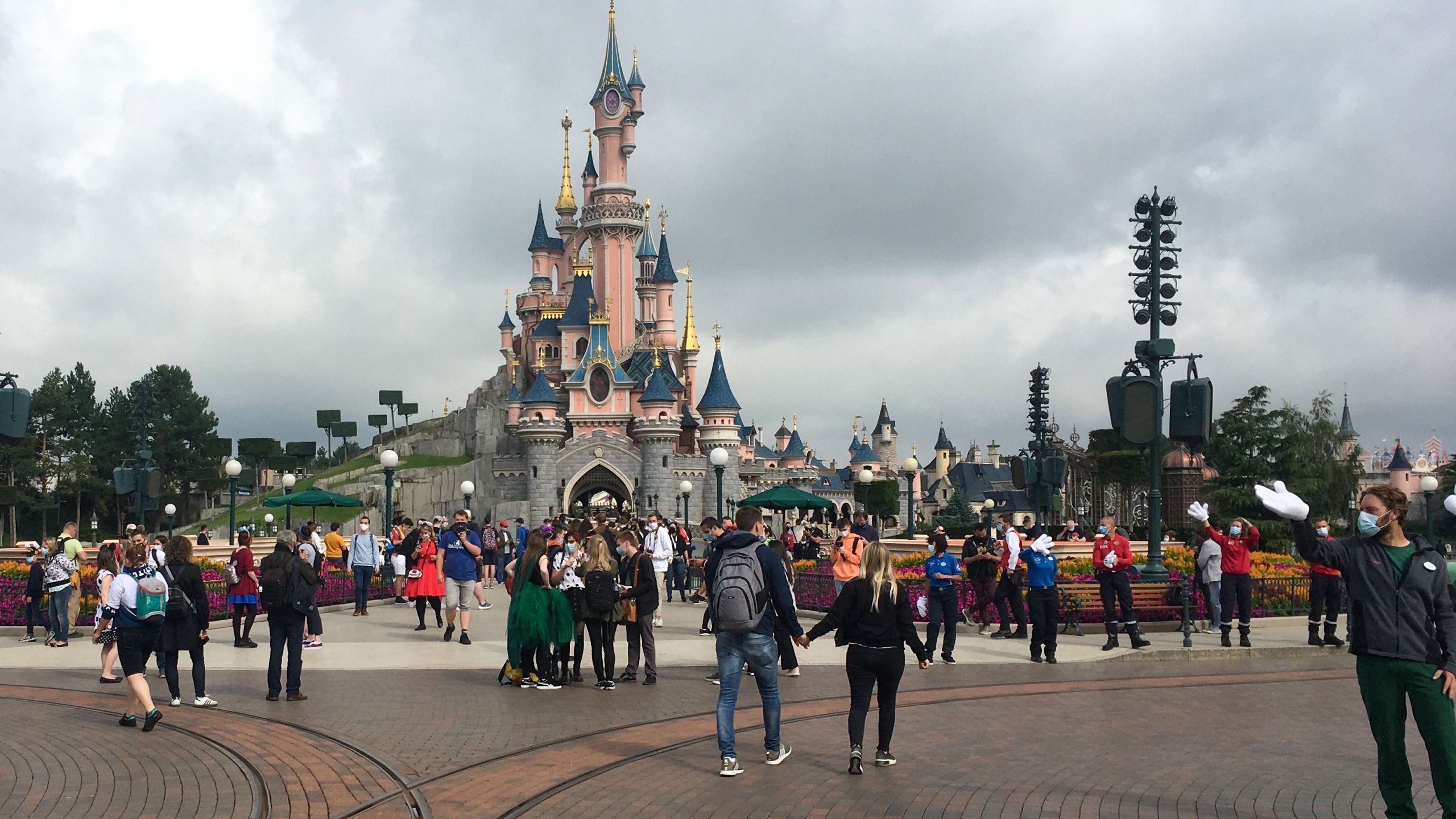 Visitors and staff wearing protective face masks walk down the Main Street of Disneyland Paris on July 15, 2020.(AURELIA MOUSSLY/AFP via Getty Images)