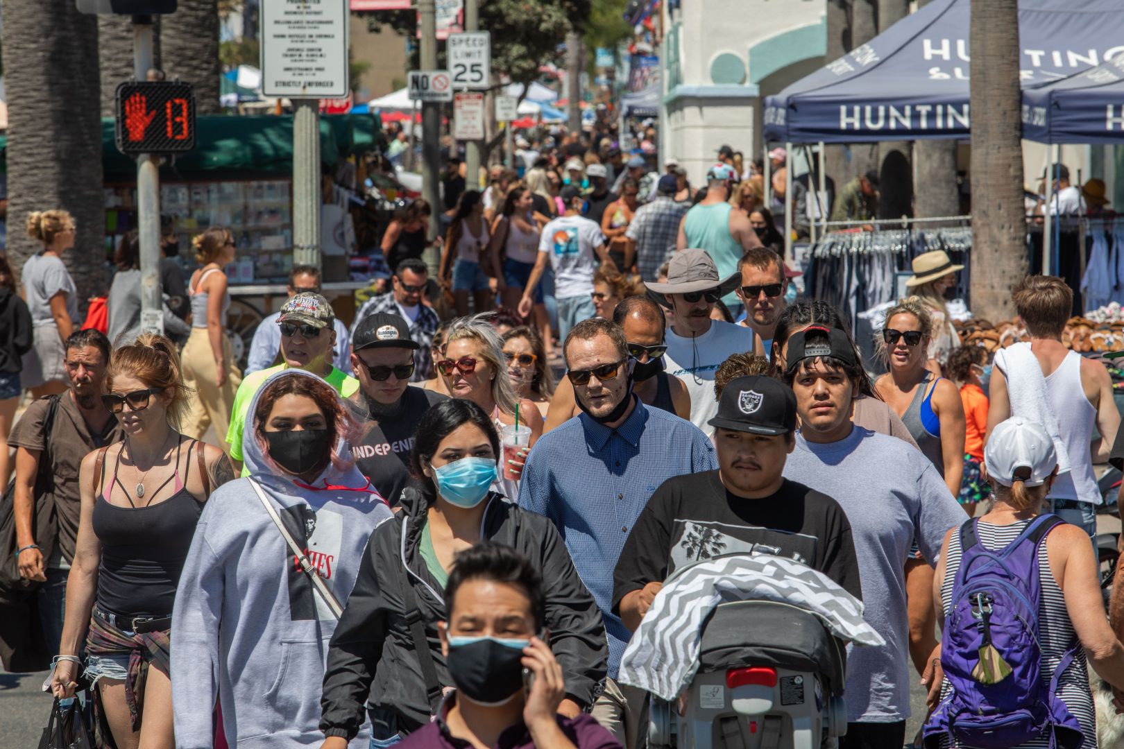 People cross the street in Huntington Beach on July 19, 2020, amid the coronavirus pandemic. (Apu Gomes / AFP / Getty Images)