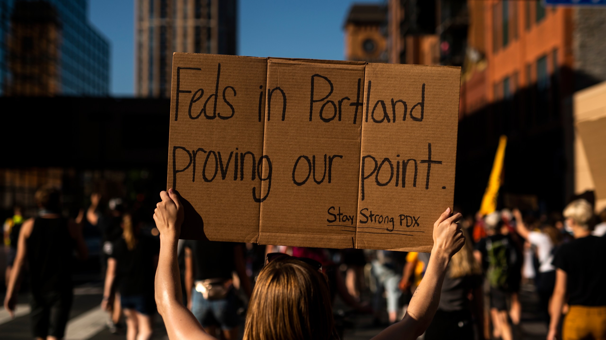 A woman marches while holding a sign that says "Feds in Portland proving our point" during a protest that started outside the Diana E. Murphy U.S. Courthouse in Minneapolis, Minnesota on July 23, 2020. (Stephen Maturen / Getty Images)