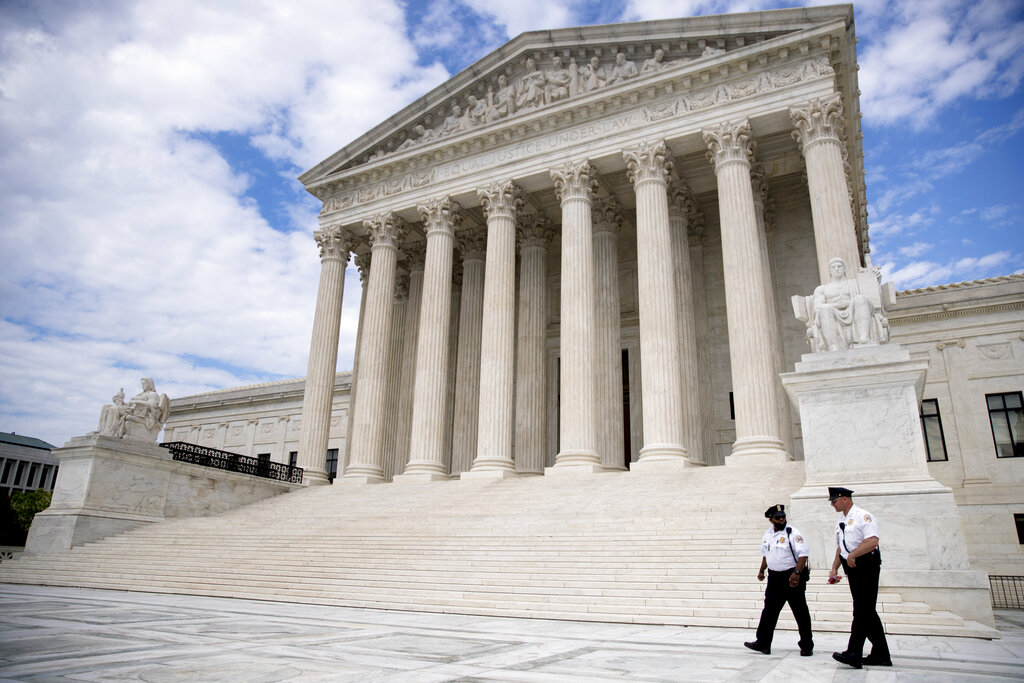 Security officers, one wearing a mask, walk in front of the Supreme Court, Thursday, May 14, 2020, in Washington. (AP Photo/Andrew Harnik)