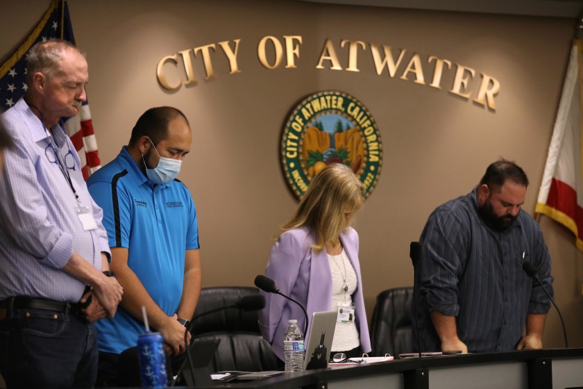 Atwater, in California’s Merced County, declared itself a “sanctuary city” from the state’s coronavirus stay-at-home orders. City Council members John Cale, left, Danny Ambriz, City Manager Lori Waterman and Mayor Pro Tem Brian Raymond bow their heads during the invocation at the start of a meeting on May 26. (Genaro Molina / Los Angeles Times)