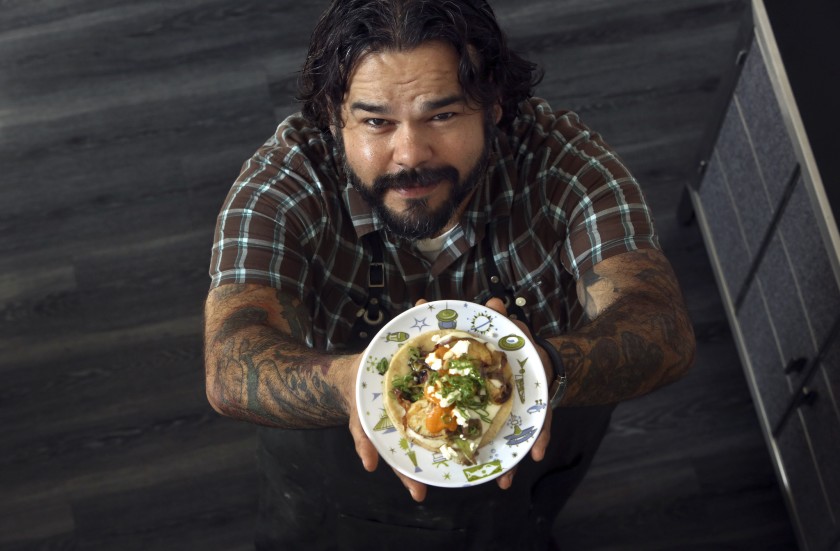 In this file photo from 2015, chef-owner Wes Avila of Guerrilla Tacos holds up his sweet potato breakfast taco, that he made at his home in Glendale.(Mel Melcon / Los Angeles Times)