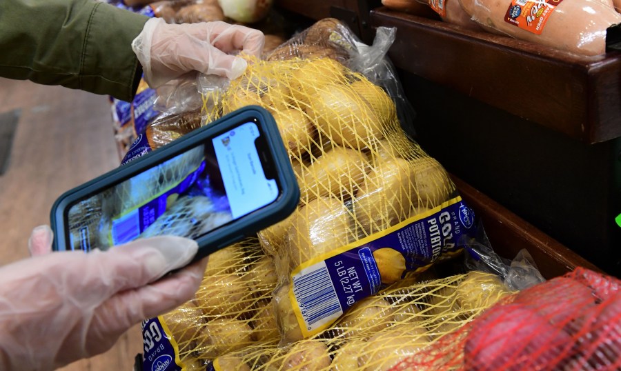 An Instacart employee uses her cellphone to scan barcodes showing proof of purchase for the customer while picking up groceries from a supermarket for delivery on March 19, 2020, in North Hollywood. (FREDERIC J. BROWN/AFP via Getty Images)