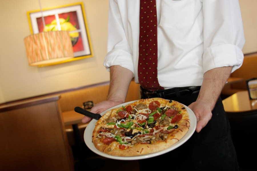 A waiter serving pizza at California Pizza Kitchen. (Jeffrey Greenberg/Universal Images Group via Getty Images)