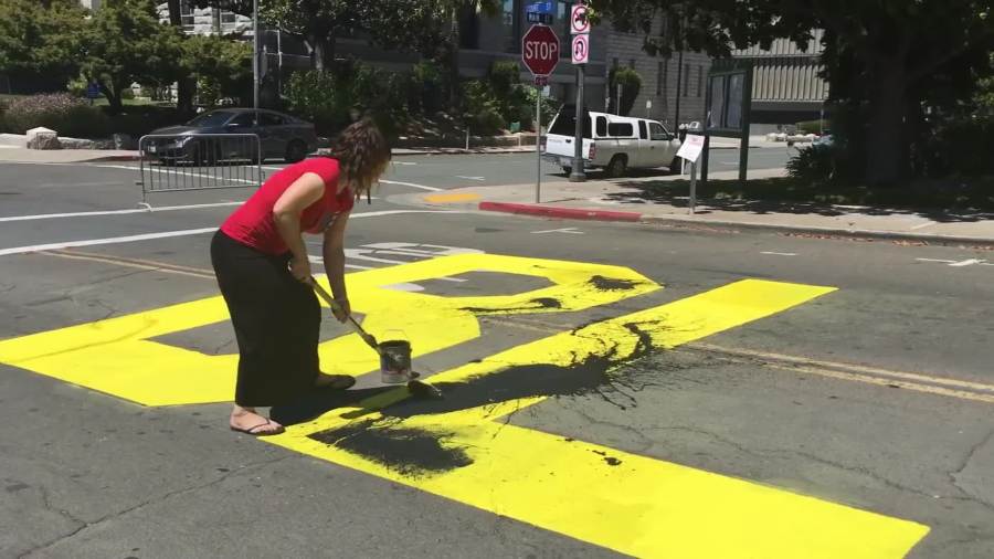 A woman paints over a Black Lives Matter mural in Martinez. (Youtube/Kerry Leidich via CNN)