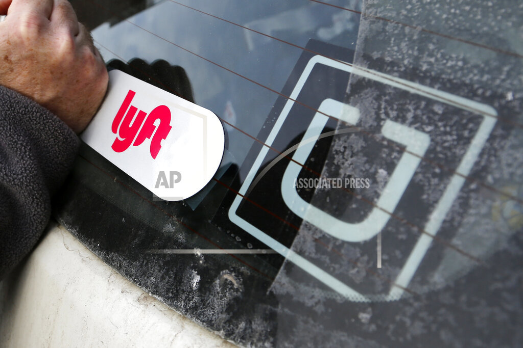 A Lyft logo is installed on a driver's car next to an Uber sticker in Pittsburgh on Jan. 31, 2018. (AP Photo/Gene J. Puskar, File)