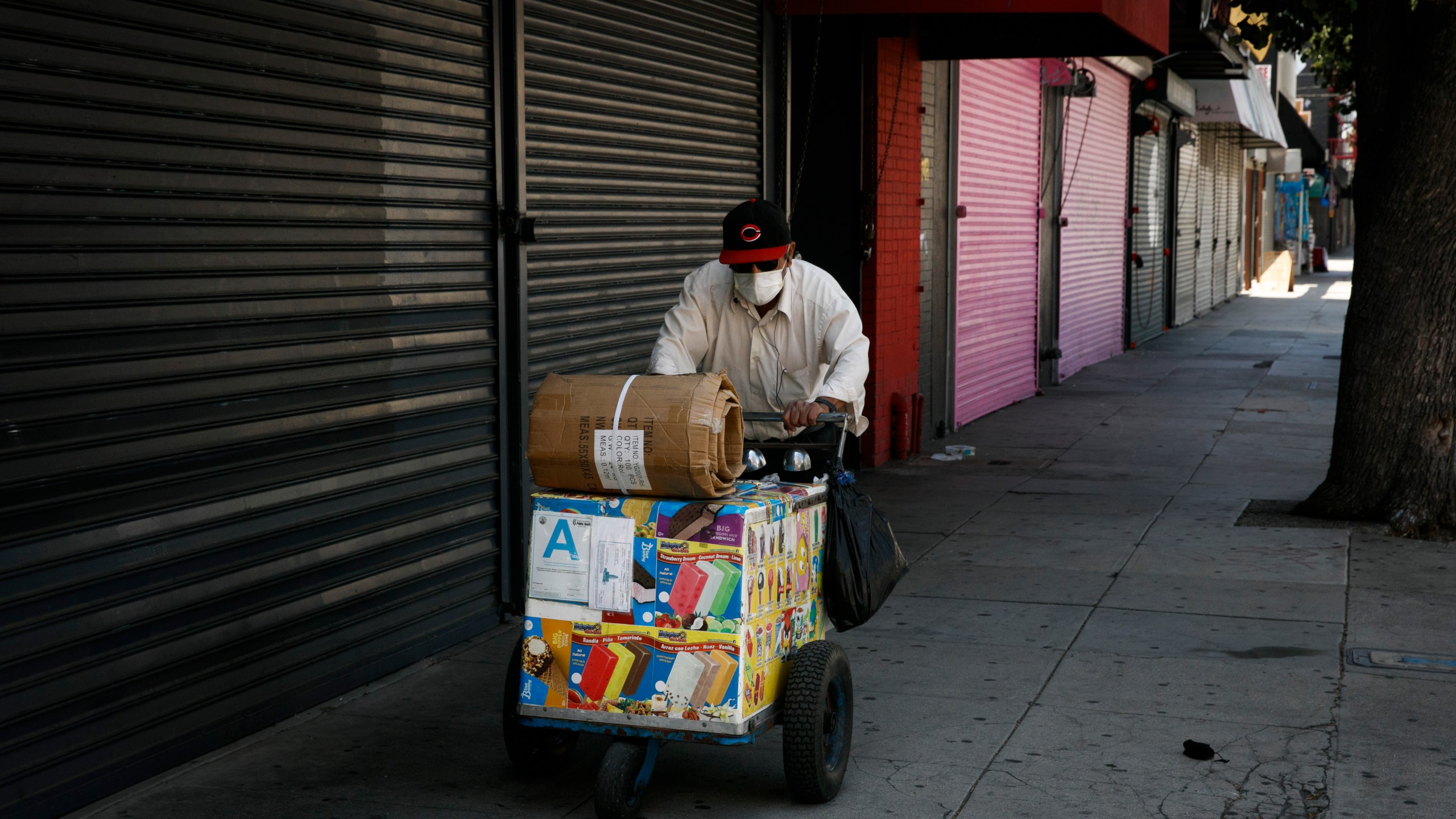 An ice cream vendor pushes his cart past shuttered stores during the coronavirus pandemic in Los Angeles on July 17, 2020. (AP Photo/Jae C. Hong)