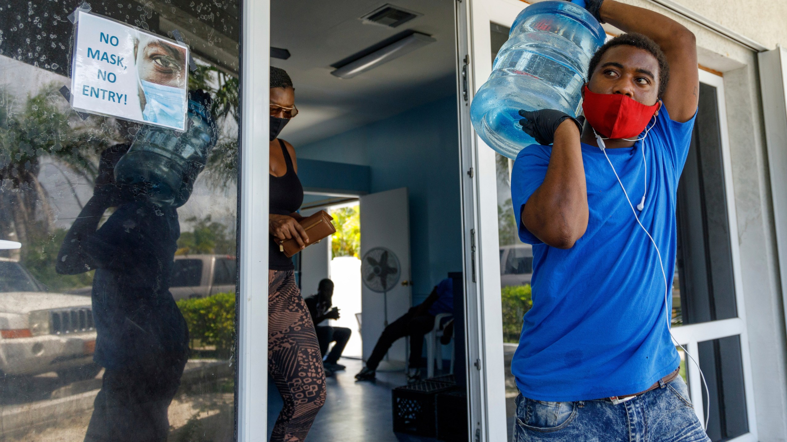 A man carries drinking water for a customer at a water depot store before the arrival of Hurricane Isaias in Freeport, Grand Bahama, Bahamas, on July 31, 2020. (AP Photo/Tim Aylen)