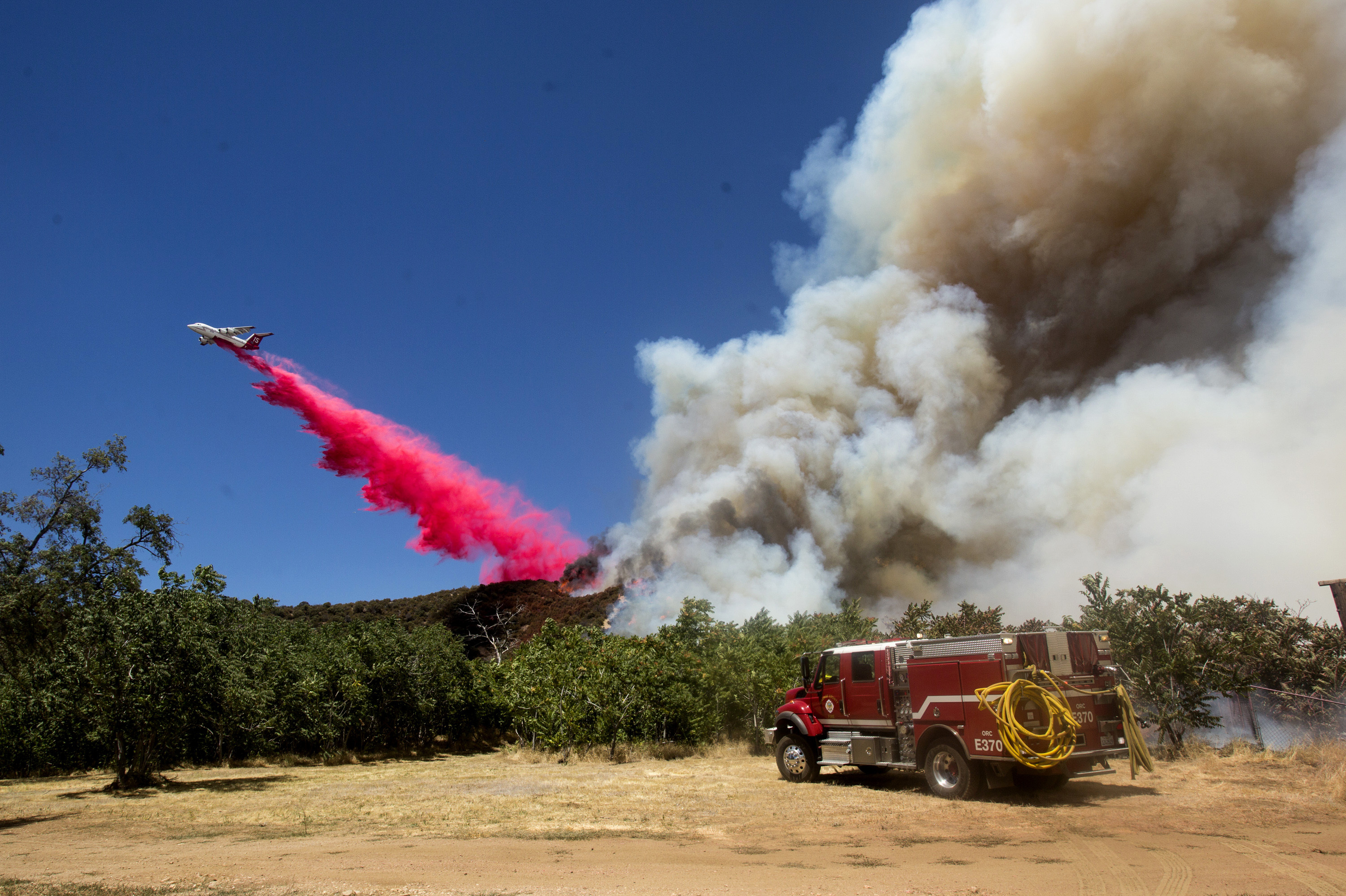 An air tanker drops fire retardant to a brush fire at the Apple Fire in Cherry Valley, Calif., Saturday, Aug. 1, 2020. (AP Photo/Ringo H.W. Chiu)