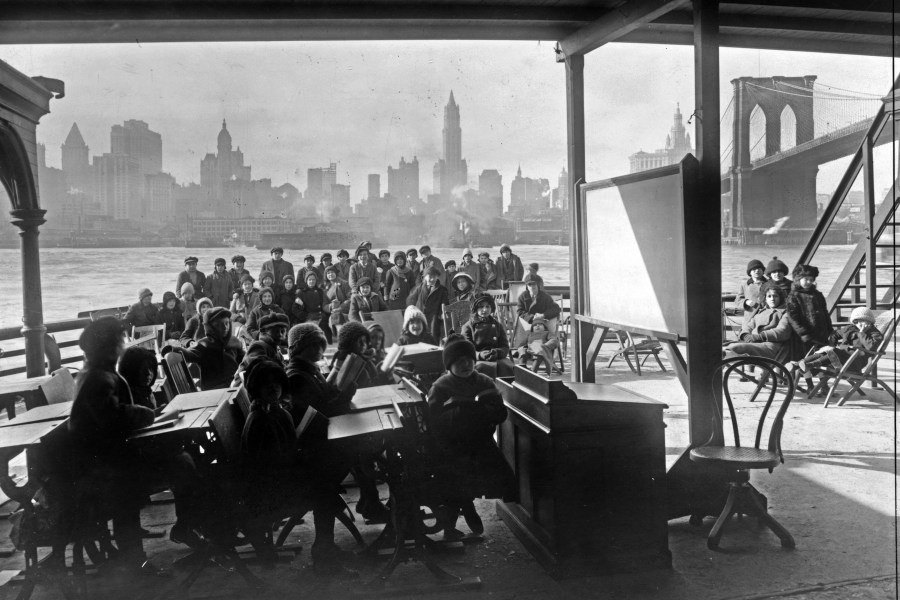 This 1911 photo from the Library of Congress shows schoolchildren on the ferry boat Rutherford, across the river from Manhattan, and near the Brooklyn Bridge, at right, in New York. (Library of Congress via AP)