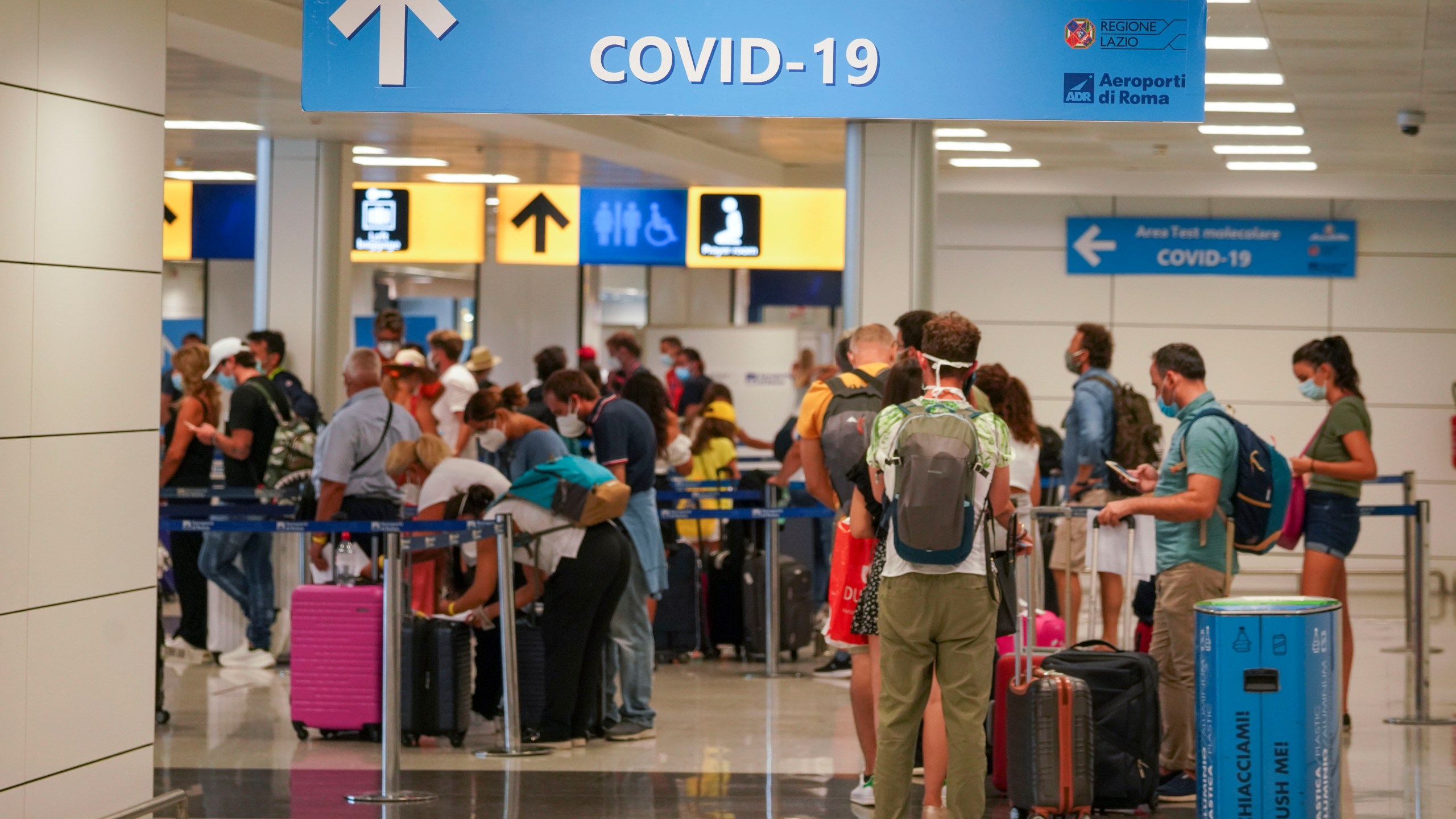 Vacationers arriving in Rome from four Mediterranean countries line up with their suitcases at Rome's Leonardo da Vinci airport to be immediately tested for COVID-19, Sunday, Aug.16, 2020. Italy's health minister issued an ordinance requiring the tests for all travelers arriving in Italy from Croatia, Greece, Malta or Spain. (AP Photo/Andrew Medichini)