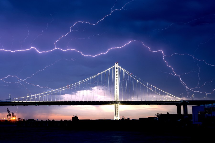 Lightning forks over the San Francisco-Oakland Bay Bridge as a storm passes over Oakland, Calif., Sunday, Aug. 16, 2020. Numerous lightning strikes early Sunday sparked brush fires throughout the region. (AP Photo/Noah Berger)