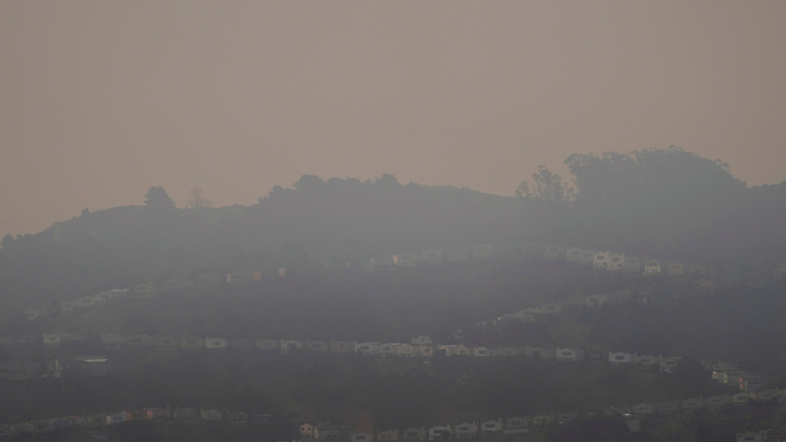 Smoke from wildfires hangs over homes in San Francisco, Wednesday, Aug. 19, 2020. Thousands of people are under orders to evacuate regions around the San Francisco Bay Area as dozens of wildfires blaze throughout the state. Smoke has blanketed the city of San Francisco and California is coping with a blistering heat wave. (AP Photo/Jeff Chiu)