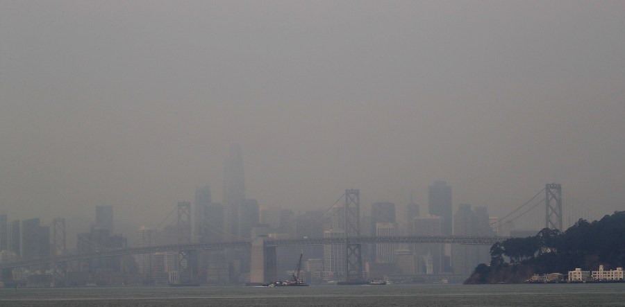 Smoke from wildfires obscures a view of the San Francisco skyline and the San Francisco-Oakland Bay Bridge on Wednesday, Aug. 19, 2020, as seen from Oakland, Calif. Crews were battling wildfires in the San Francisco Bay Area and thousands of people were under orders to evacuate Wednesday as hundreds of wildfires blazed across the state amid a blistering heat wave now in its second week. (AP Photo/Ben Margot)