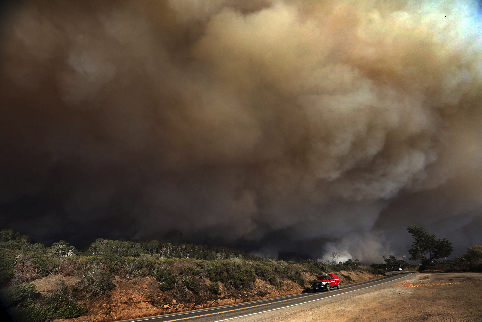 A massive column of smoke rises above Highway 1 just north of the Santa Cruz County line as a section of the CZU August Lightning Complex burns above Waddell Beach, on Aug. 19, 2020, northwest of Santa Cruz, Calif. (Shmuel Thaler/The Santa Cruz Sentinel via AP)