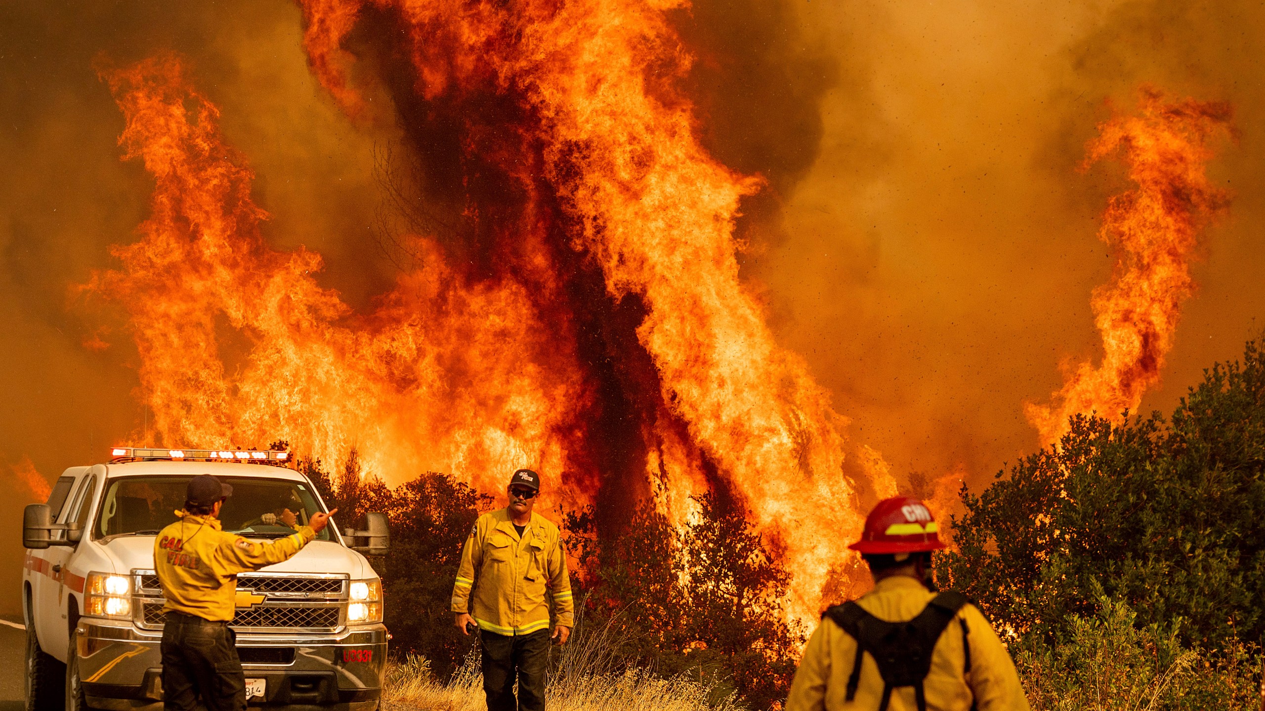 Flames from the LNU Lightning Complex fires leap above Butts Canyon Road on Sunday, Aug. 23, 2020, as firefighters work to contain the blaze in unincorporated Lake County, Calif. (AP Photo/Noah Berger)