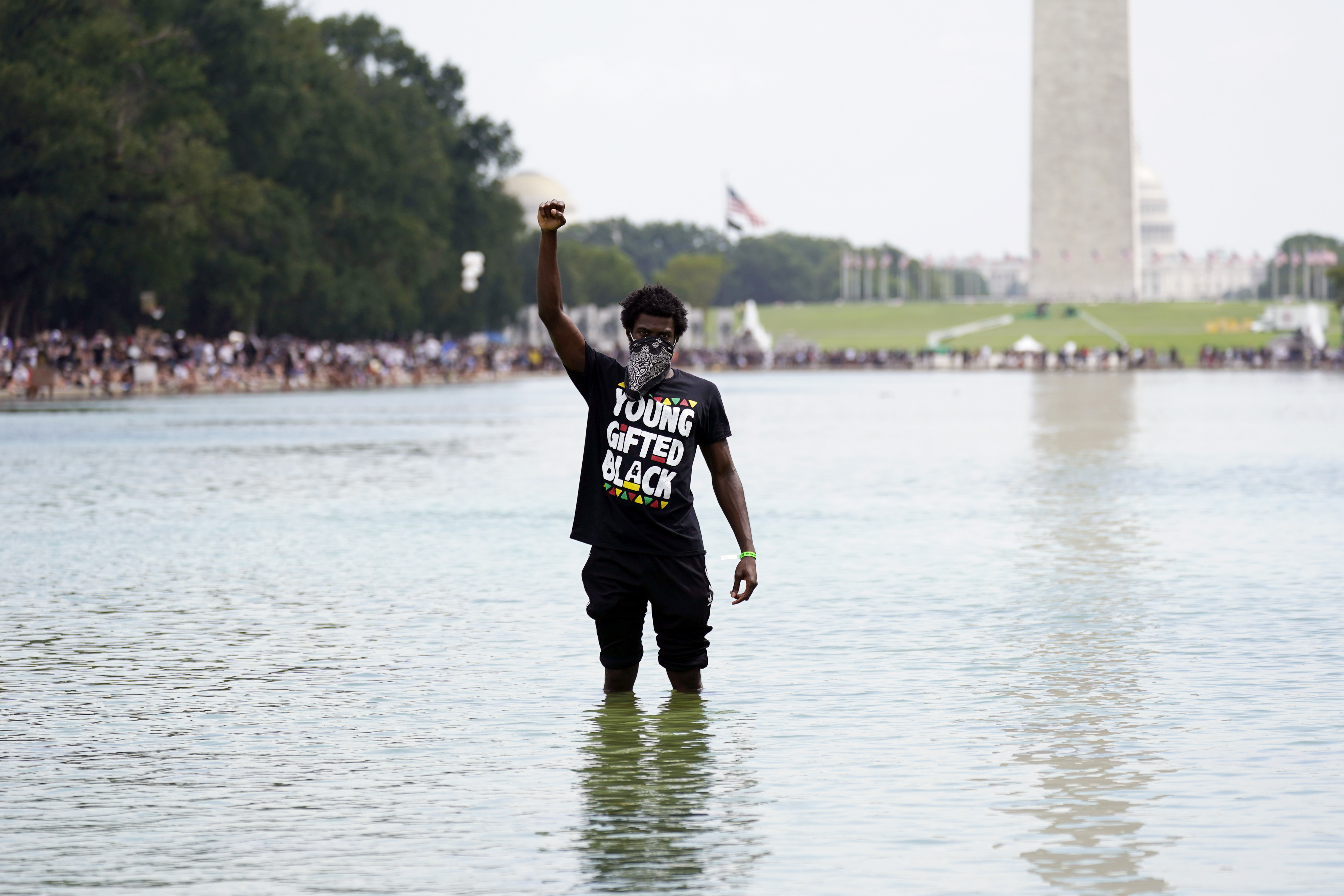 A man stands in the Reflecting Pool as people attend the March on Washington on Aug. 28, 2020, on the 57th anniversary of the Rev. Martin Luther King Jr.'s "I Have A Dream" speech. (Carolyn Kaster / Associated Press)