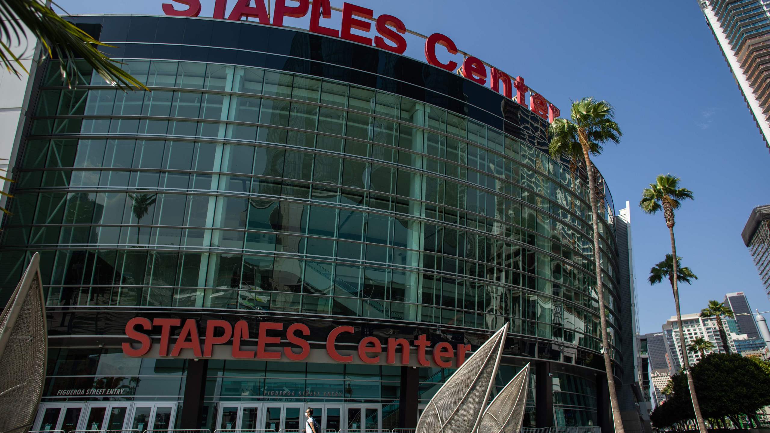 A man wearing a face mask walks in front of the Staples Center in downtown Los Angeles on May 9, 2020. (Apu Gomes / AFP via Getty Images)