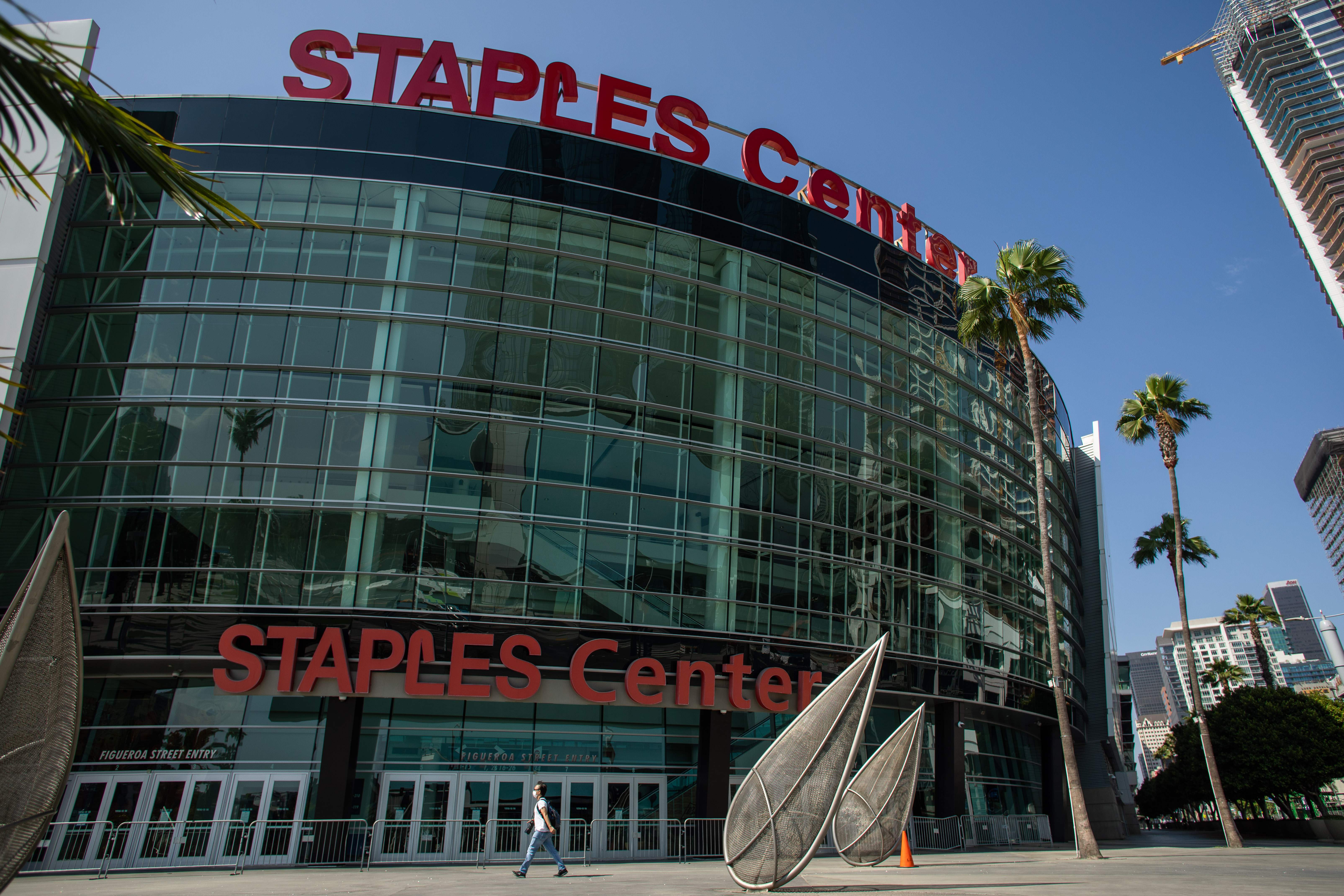 A man wearing a face mask walks in front of the Staples Center in downtown Los Angeles on May 9, 2020. (Apu Gomes / AFP via Getty Images)