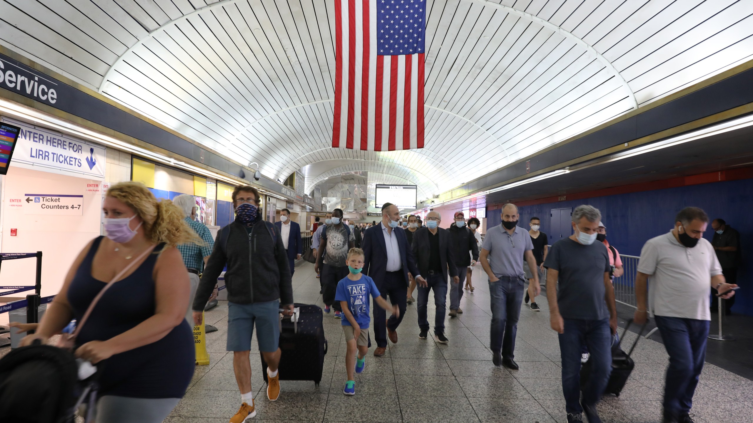 People walk through Pennsylvania Station as city workers attempt to hand out information sheets to travelers arriving by train from states affected by rules requiring 14-day quarantines on Aug. 6, 2020 in New York City. New York City Mayor Bill de Blasio announced that units to enforce the new rules will establish COVID-19 quarantine checkpoints at various bridges, tunnels, train stations and other points of entry as New York works to contain the pandemic. (Spencer Platt/Getty Images)