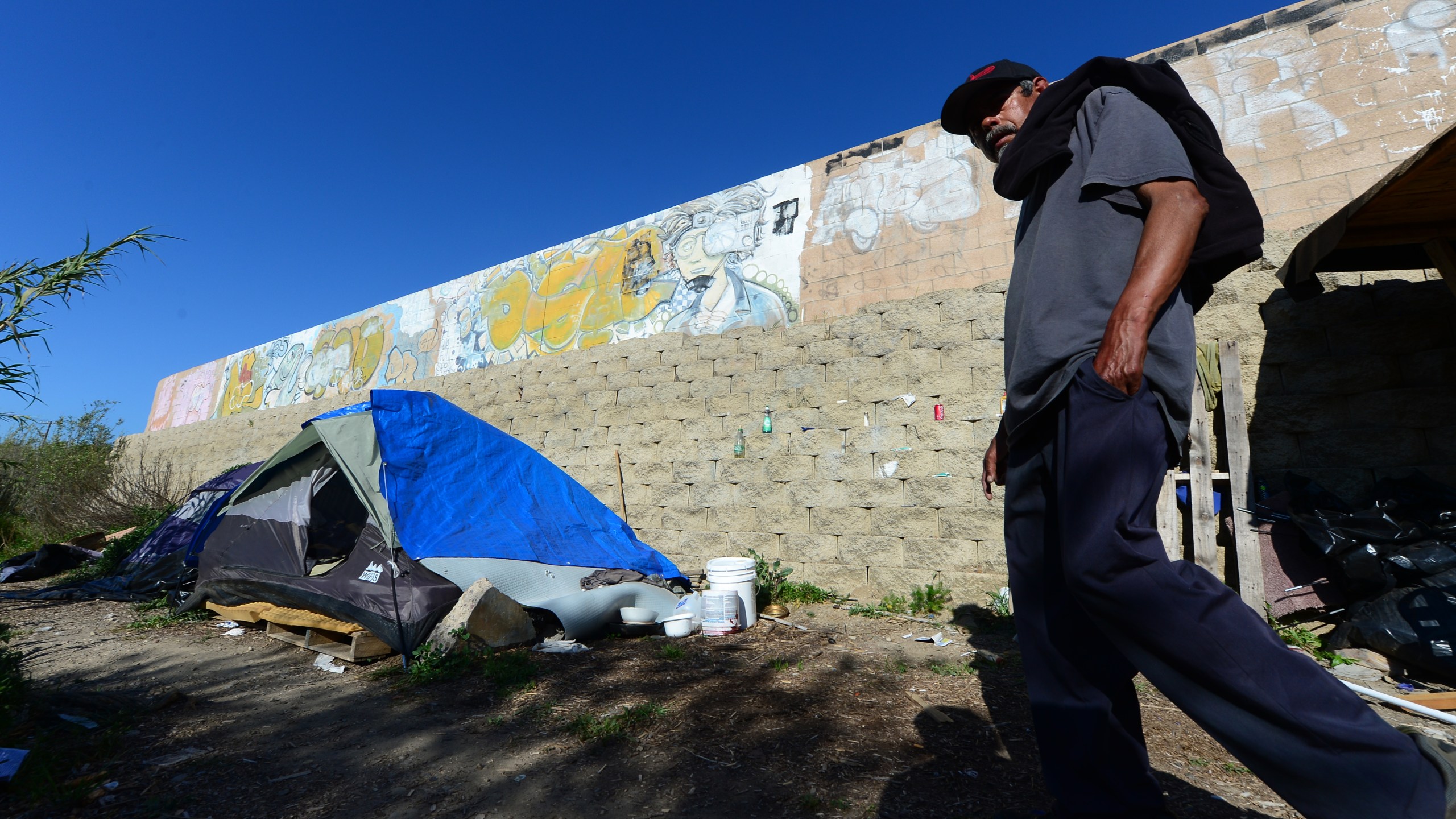 Enrique Mornones, an advocate for social justice, delivers water to the homeless and undocumented individuals who live beside a wall in a canyon in San Diego, California on April 4, 2013, including this 64-year old man named Pedro, who said he has lived here for ten years. Morones founded 'Border Angels' in 1986, taking a chance to make a difference, helping save the lives of legions of desperate travelers who attempt to cross the hot, beautiful and dangerous deserts that straddle the United States and Mexico. (FREDERIC J. BROWN/AFP via Getty Images)