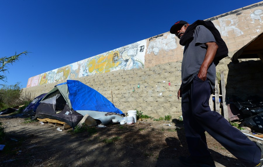 Enrique Mornones, an advocate for social justice, delivers water to the homeless and undocumented individuals who live beside a wall in a canyon in San Diego, California on April 4, 2013, including this 64-year old man named Pedro, who said he has lived here for ten years. Morones founded 'Border Angels' in 1986, taking a chance to make a difference, helping save the lives of legions of desperate travelers who attempt to cross the hot, beautiful and dangerous deserts that straddle the United States and Mexico. (FREDERIC J. BROWN/AFP via Getty Images)