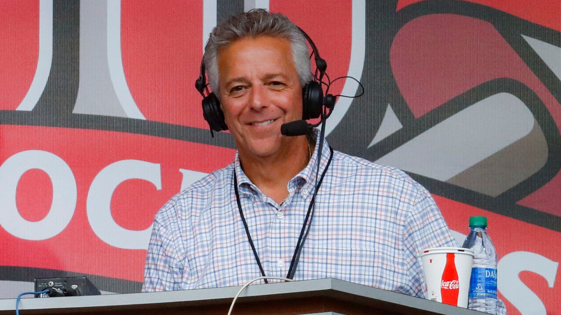 In this Sept. 25, 2019, file photo, Cincinnati Reds broadcaster Thom Brennaman sits in a special outside booth before the Reds' baseball game against the Milwaukee Brewers in Cincinnati. (AP Photo/John Minchillo, File)