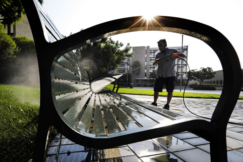 In this undated photo, Brett Nickman power-washes benches at Cal State Fullerton in preparation for the school’s reopening for the fall semester.(Irfan Khan / Los Angeles Times)