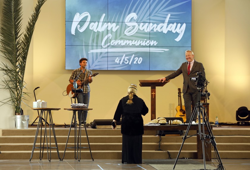 Pastor Rob McCoy, right, gives Communion at an April 5 Palm Sunday service at his Thousand Oaks church, Godspeak Calvary Chapel. (Carolyn Cole / Los Angeles Times)