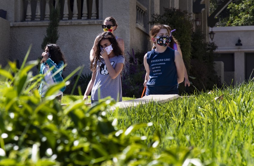 Wearing masks for protection, Rosie Roth, left, Penelope Roth and Ellie Bristow walk to a cooking class during home school in the midst of the coronavirus pandemic in Riverside. (Gina Ferazzi / Los Angeles Times)