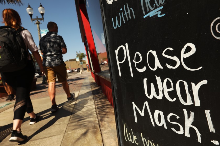 Some restaurateurs in Mammoth Lakes, part of Mono County, believe they have been scapegoated because of state snafus in monitoring coronavirus cases. Above, a “Please Wear Mask” reminder in Huntington Beach. (Genaro Molina / Los Angeles Times)