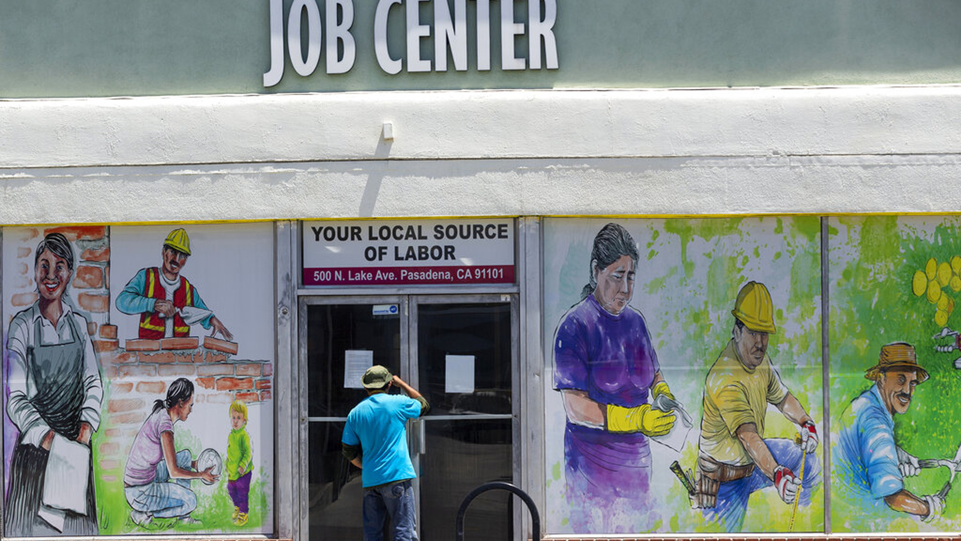 In this May 7, 2020, photo, a person looks inside the closed doors of the Pasadena Community Job Center in Pasadena during the coronavirus outbreak. (AP Photo/Damian Dovarganes, File)